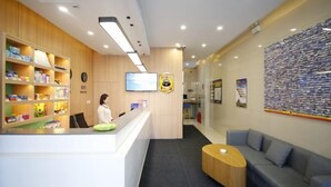 A reception area with a counter, a woman behind it, and a wall with a poster. - Super 8 Inn Jilin Shenzhen Street (Jilin City)