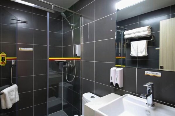 Ein modernes Badezimmer mit einer gläsernen Duschkabine, einem weißen Waschbecken und einem Handtuchhalter.