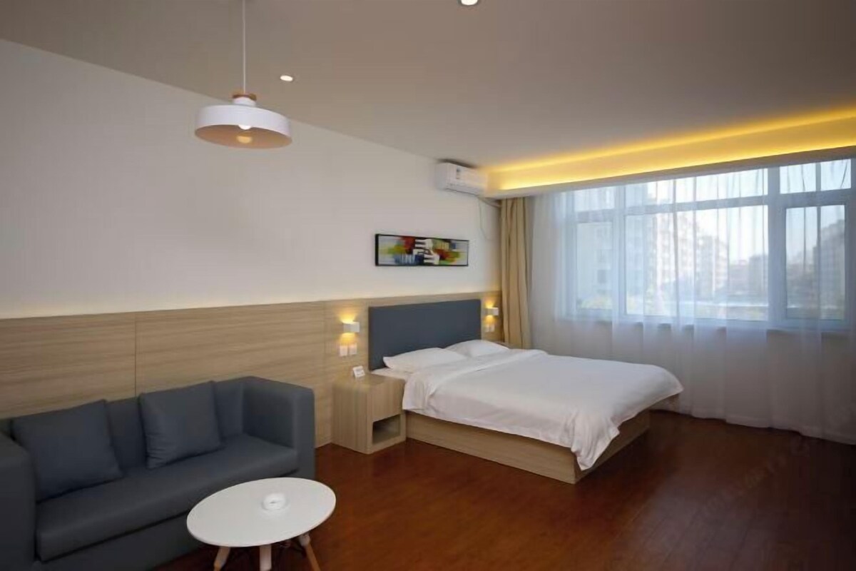 Ein Hotelzimmer mit Bett, Sofa, kleinem Tisch, Nachttisch und einem Bild an der Wand.