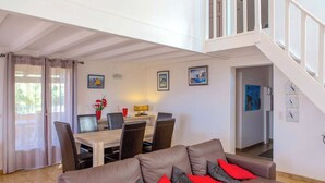 A spacious living area with a brown leather sofa, a dining table with chairs, and a staircase leading to an upper level. - 10 people sea view villa with pool in the south part of Corsica (Olmeto, Abbartelo)