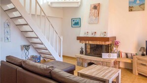 A living room with a staircase, a fireplace, and a bookshelf. - 10 people sea view villa with pool in the south part of Corsica (Olmeto, Abbartelo)