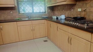 Uma cozinha com armários de madeira, fogão a gás e janela com persianas.
