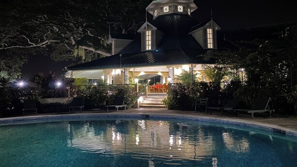 A nighttime view of a hotel with a pool, a covered patio, and a tower with a dome. - The Royal Hotel (San Fernando)