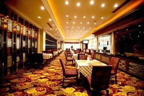 Un restaurante con varias mesas y sillas, un suelo estampado e iluminación empotrada en el techo.
