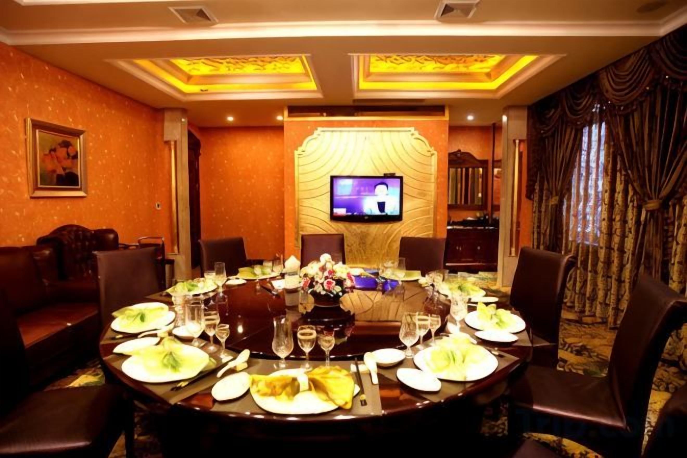 Un salón de conferencias con una mesa redonda dispuesta para una reunión, equipado con una pantalla de televisión y rodeado de sillones de cuero.