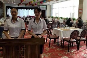 A restaurant with round tables and chairs, a red carpet, and a ceiling with hanging decorations.