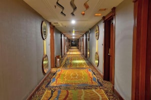 A hotel hallway with a patterned carpet, wooden doors, and circular wall decorations.