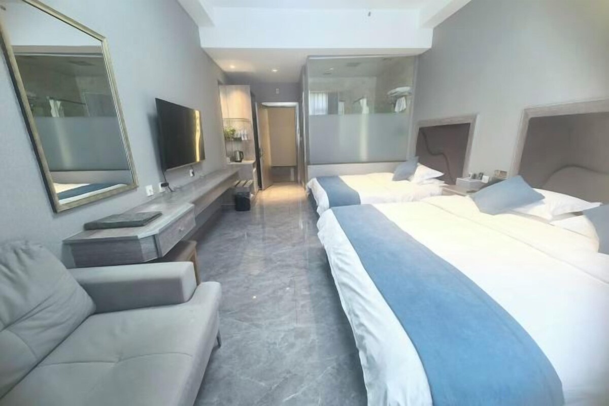 A hotel room with a bed, a sofa, a TV, and a mirror.