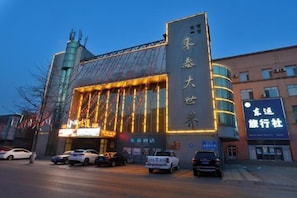 Un edificio con señalización iluminada y un letrero vertical grande.