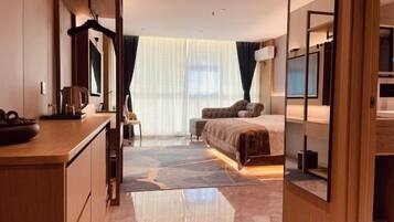A hotel room with a bed, a desk, a chair, a mirror, and a large window with curtains.