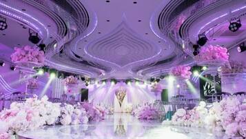 A stage with floral arrangements and a central podium, surrounded by seating.