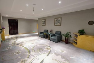Un hall de hotel con alfombra floral, una zona de estar y un mostrador de recepción.