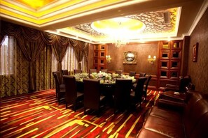 Un comedor formal con una araña, cortinas estampadas y un suelo cubierto de alfombra roja.