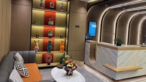 A modern reception area with a marble counter, a sofa with patterned cushions, and a shelf with decorative items. - Dongtai Dashijie Hotel (Kuandian)