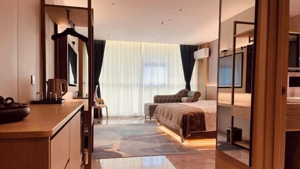 A modern hotel room with a bed, a desk, and a mirror. - Dongtai Dashijie Hotel (Kuandian)