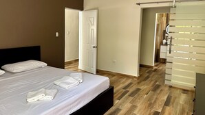 Una habitación de hotel con una cama, un armario y un baño visible a través de una puerta abierta.