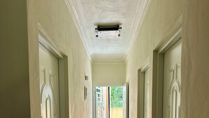 Un pasillo con puertas blancas, piso de baldosas y un respiradero en el techo.