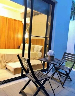 Relax in a serene bedroom with a sliding glass door leading to an outdoor space featuring a bench and a small table.