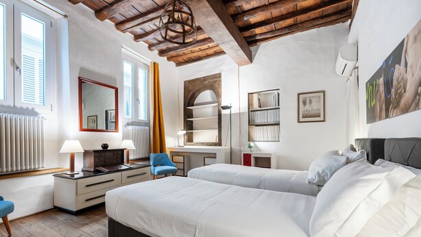 Een slaapkamer met een groot bed, een bureau, een stoel en een kledingkast.