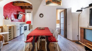 Een eethoek met een rode tafelkleed, witte stoelen en een houten plafond.