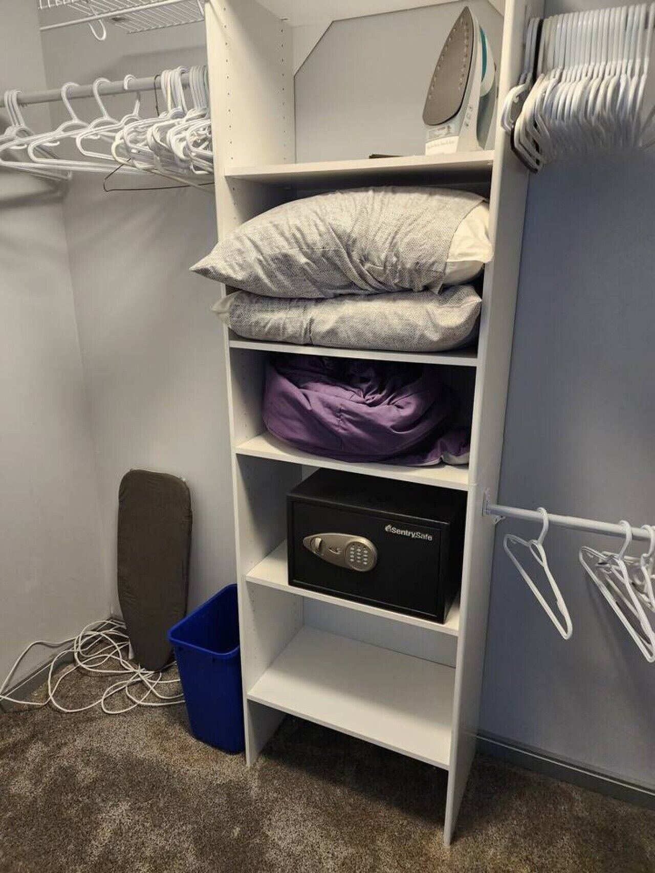 A closet with shelves holding clothes, a mattress, a mattress protector, a storage box, and a radiator.
