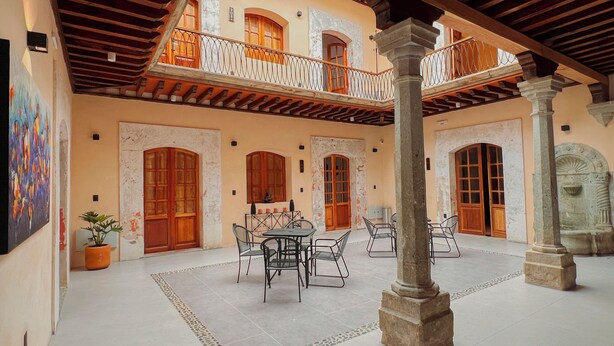Un amplio patio con suelo de baldosas, una mesa central con sillas y una barandilla decorativa.