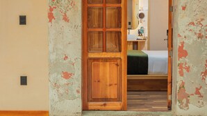 Una habitación con una puerta de madera grande que da a un dormitorio.