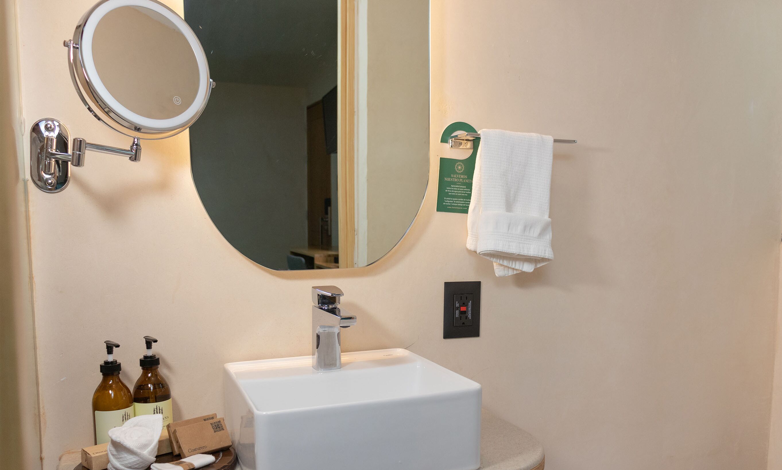 A bathroom with a white sink, a mirror, a towel rack, and toiletries.