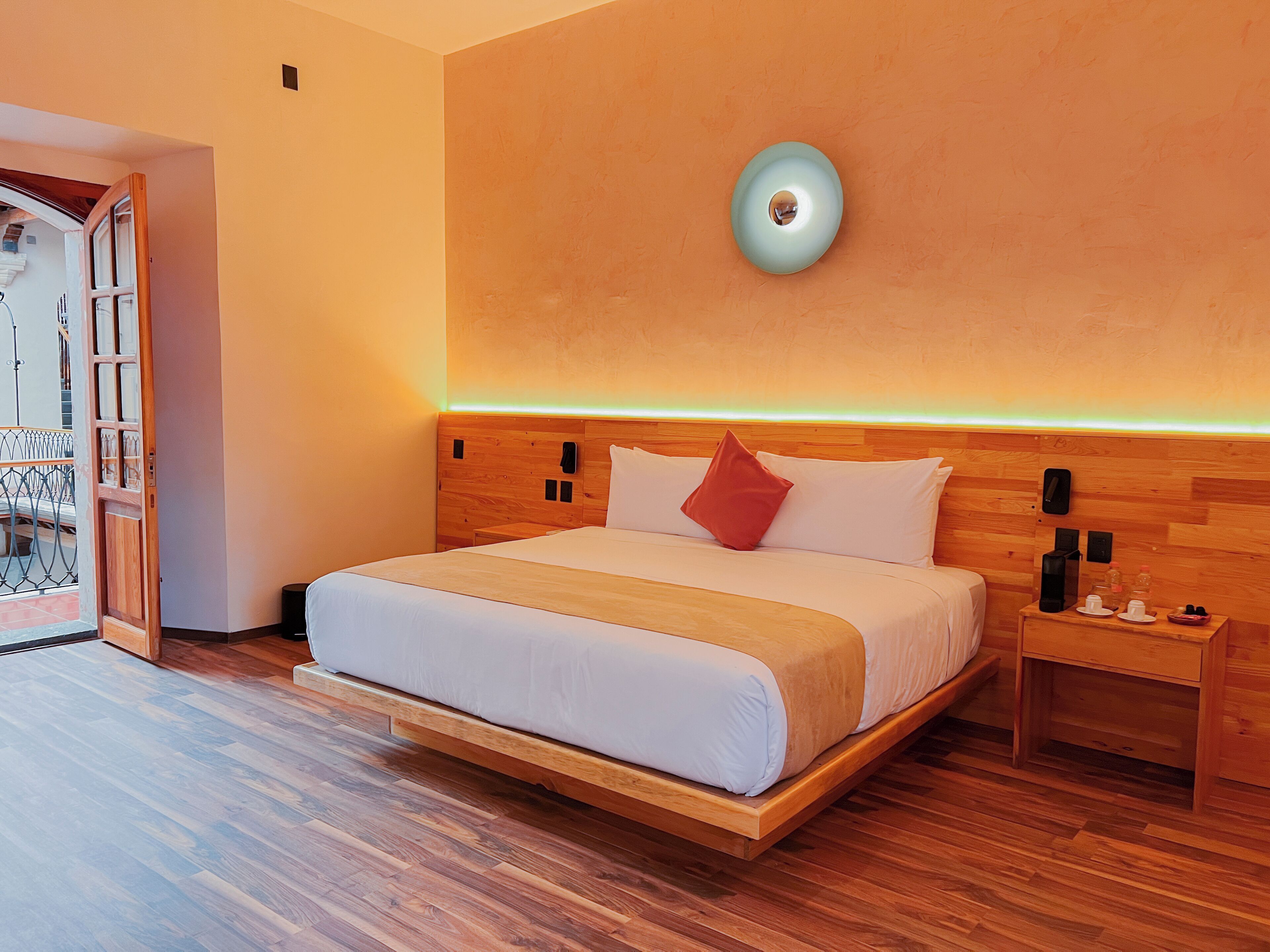 A modern hotel room with a wooden bed, a bedside table, and a nightstand.