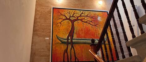 A staircase with a wooden handrail and a wall-mounted painting of a tree and canoe.