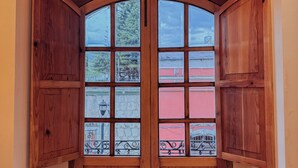 Una puerta de madera con paneles de vidrio y una vista a un balcón con barandillas y un edificio al fondo.