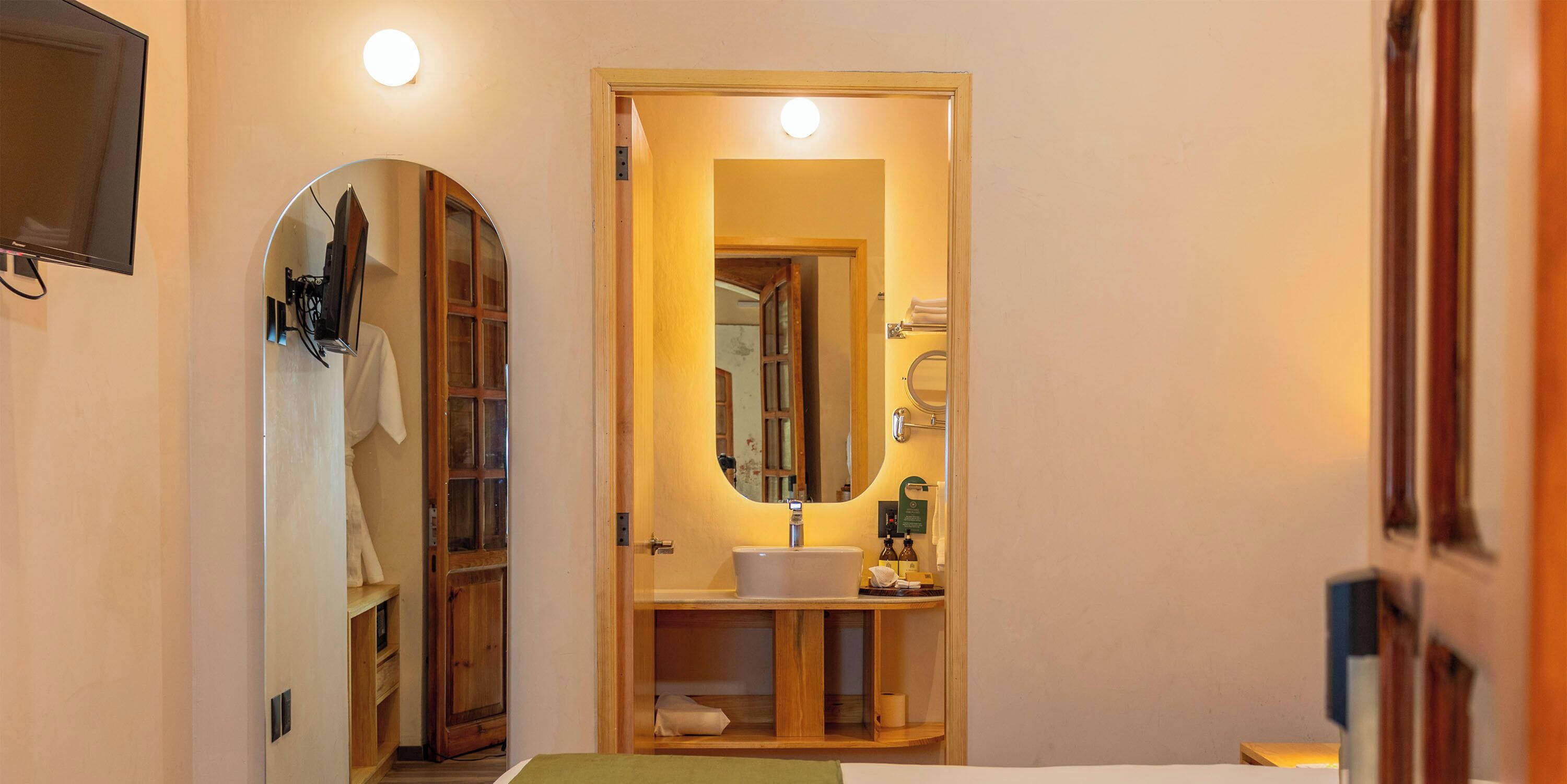 Una habitación de hotel con una cama, un espejo, un lavamanos y un armario de madera.