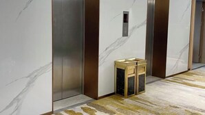 Een moderne lift met marmeren wanden en een patroon vloer.