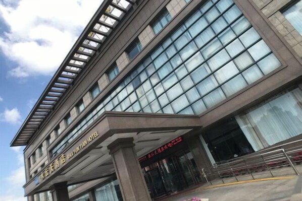 Un moderno edificio de hotel con grandes ventanales y un letrero que indica que es el Hotel Shiyun Tian.