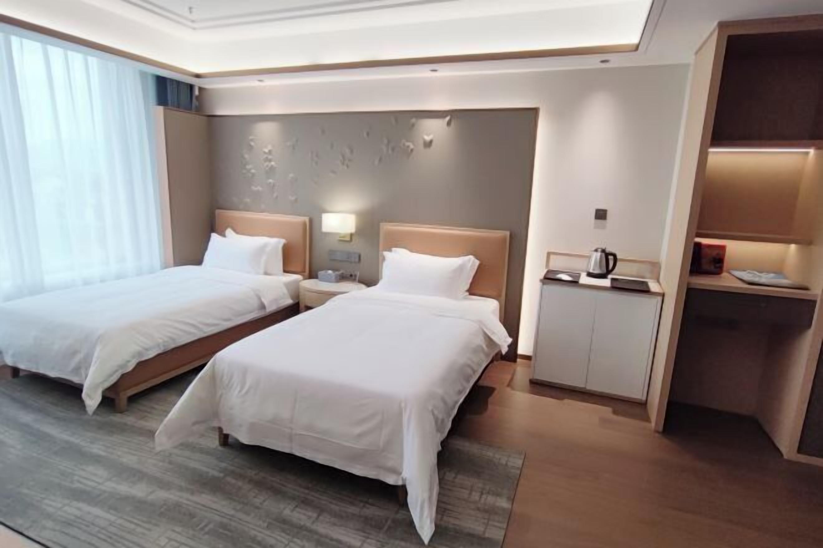 Une chambre d’hôtel avec deux lits, un bureau, une machine à café et une table de chevet.