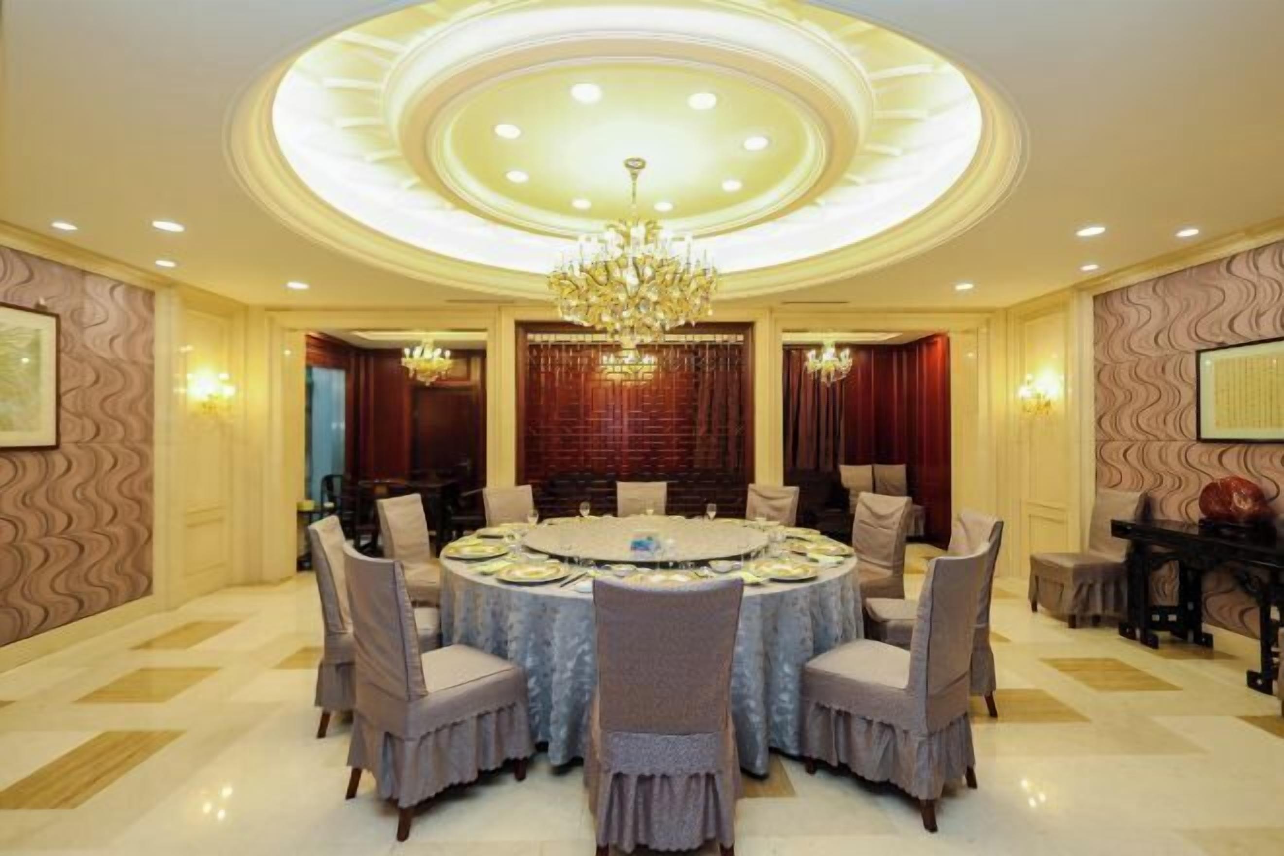 A formal dining room with a round table, chairs, and a chandelier.