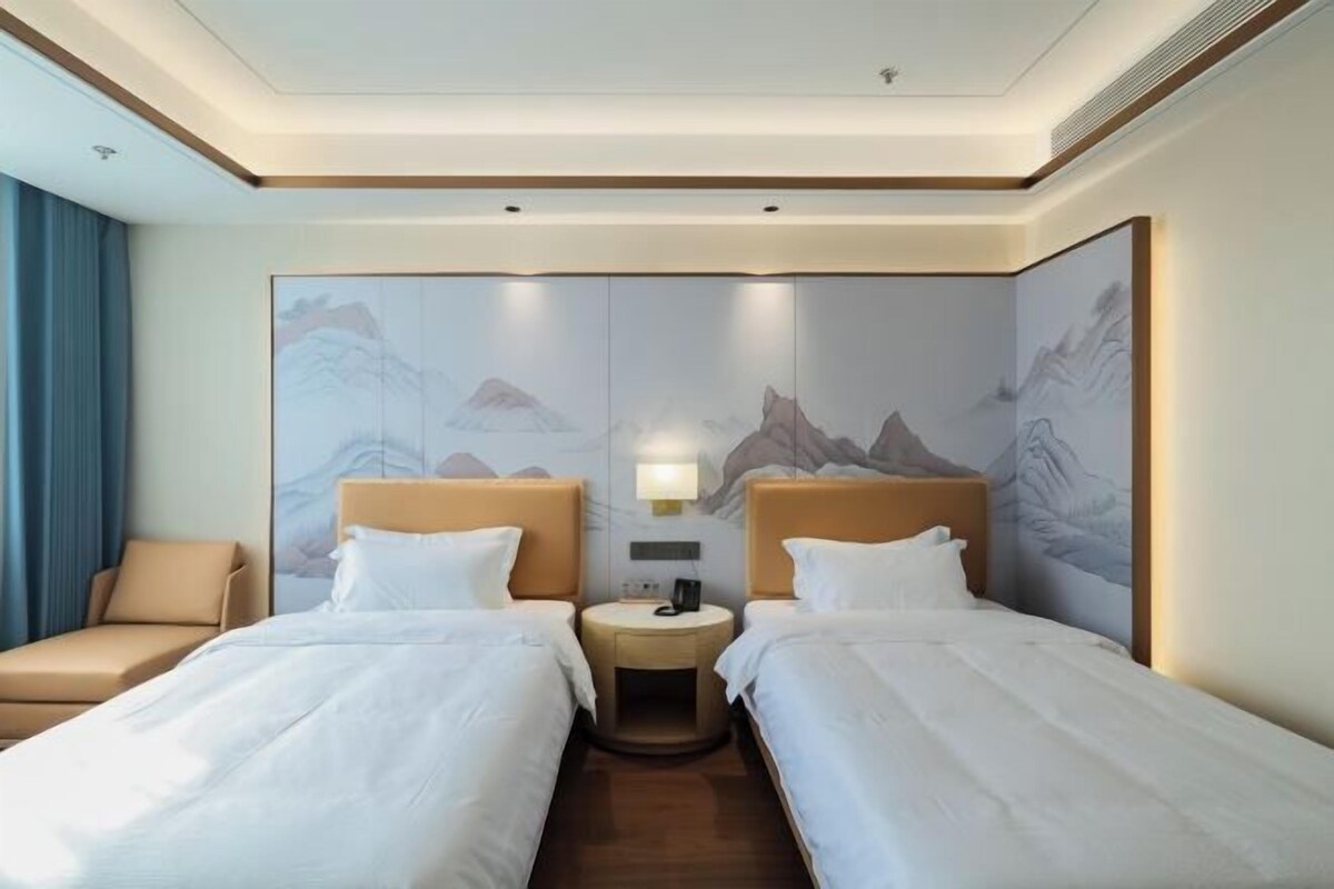 Habitación de hotel con dos camas, una mesita redonda y una silla.