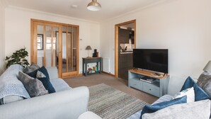 A living room with a sofa, TV, and a small table with books.
