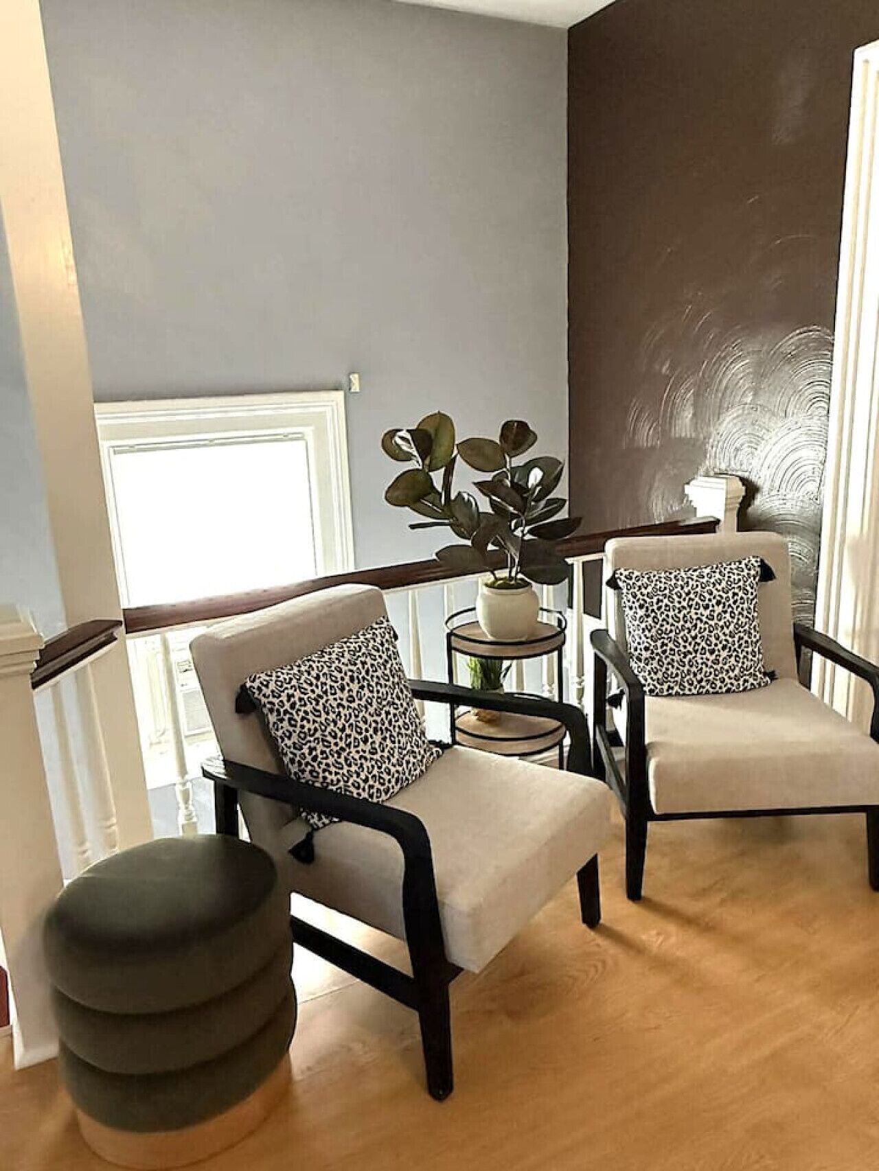 A modern living room with two armchairs, a side table, and a potted plant.