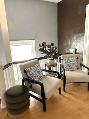 A modern living room with two armchairs, a side table, and a potted plant.