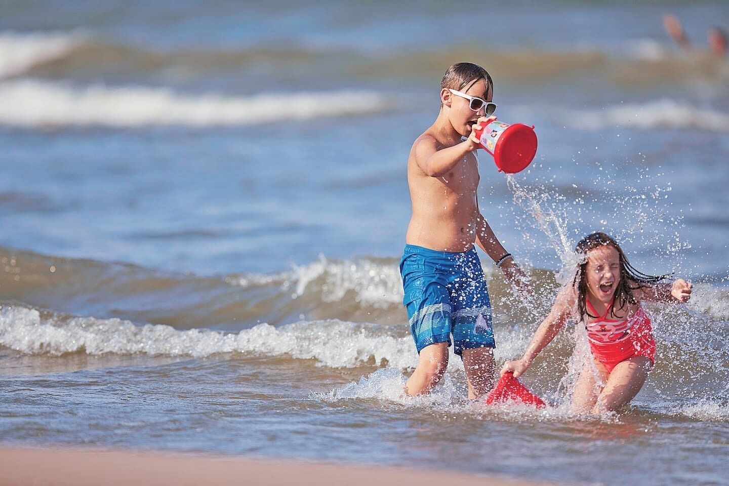 Two children playing in the water at the beach.