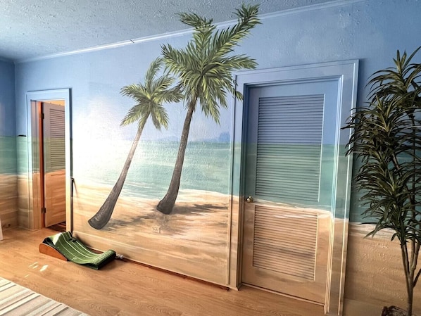 A room with a beach-themed mural, a sliding door, and a green chair.