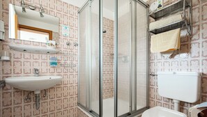 Ein Badezimmer mit Dusche, Waschbecken, Toilette und Handtuchhalter.