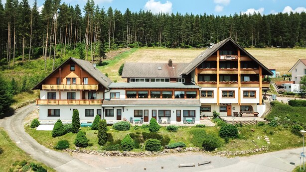 Eine große, mehrstöckige Lodge mit einem markanten Balkon und einer Seilbahn im Hintergrund.
