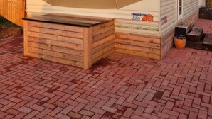 Una casa móvil con porche cubierto, una pequeña terraza y una ventana con cortinas.