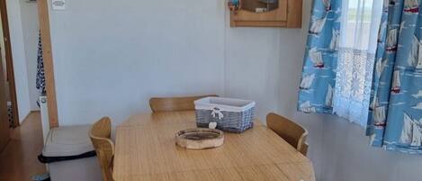 A dining area with a round wooden table, four chairs, a cabinet with a model house, and a sign that reads "Beach Side."