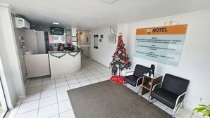 A hotel reception area with a Christmas tree, a reception desk, and a signboard. - Ok Inn Hotel Tubarão (Tubarao)