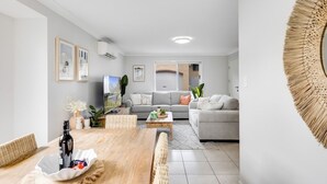 Una sala de estar moderna con comedor, sofás grises y un espejo decorativo grande.