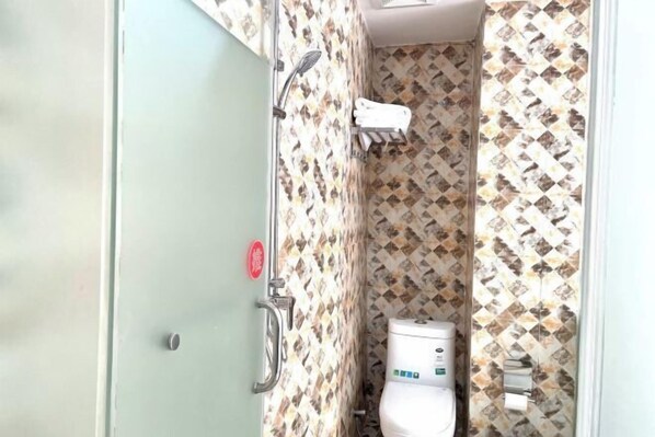 A bathroom with a toilet, a towel rack, and a shower area.