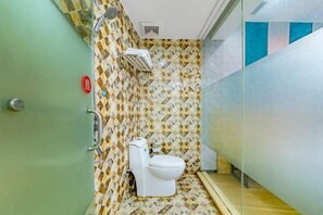 Un baño pequeño con inodoro, ducha y piso de baldosas estampadas.